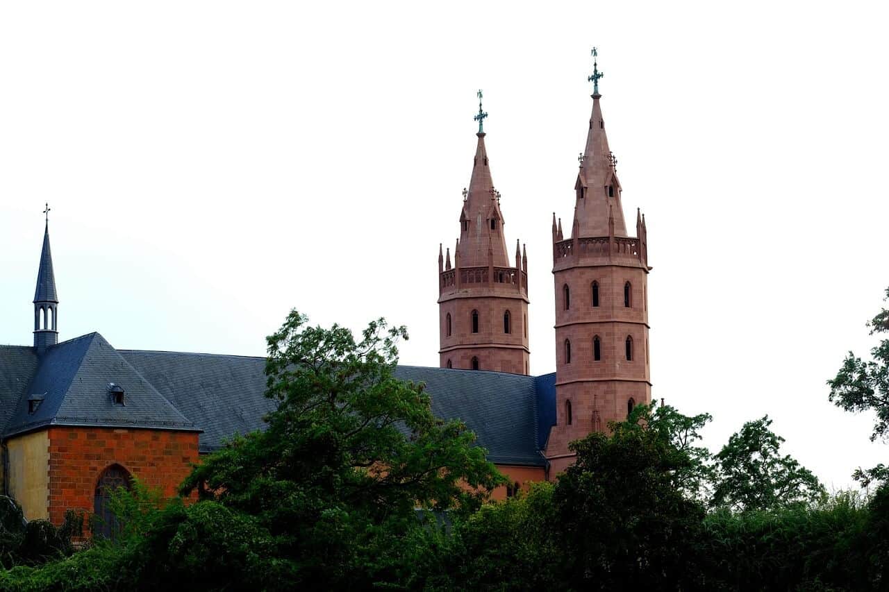 Liebfrauenkirche in Worms mit zwei Türmen, über Bäumen und Häusern sichtbar.