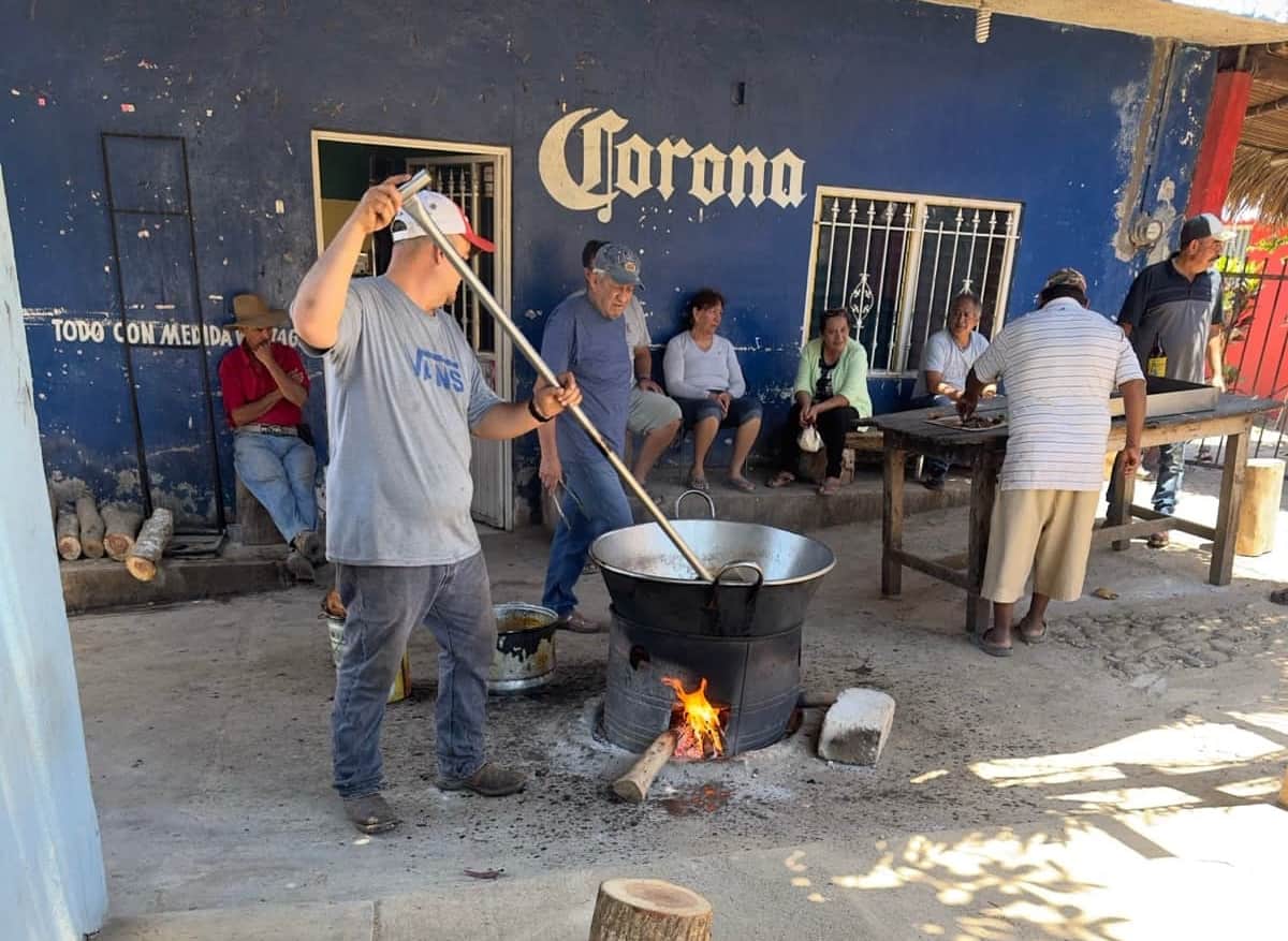 Carnitas cooking in a copper pot over a wood fire on the street in Altavista, Nayarit