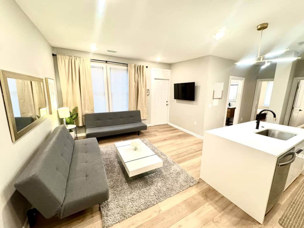 spacious living room! It features 2 futon sofa beds, perfect for accommodating extra guests. Enjoy your favorite shows on the 50-inch TV,  Cozy up by the fireplace underneath for a warm atmosphere. There’s a door that leads to a small balcony outside