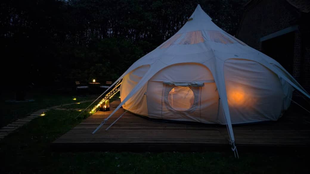 Magische Nächte am Limfjord: Das gemütlich leuchtende Glamping-Zelt auf der Holzterrasse.