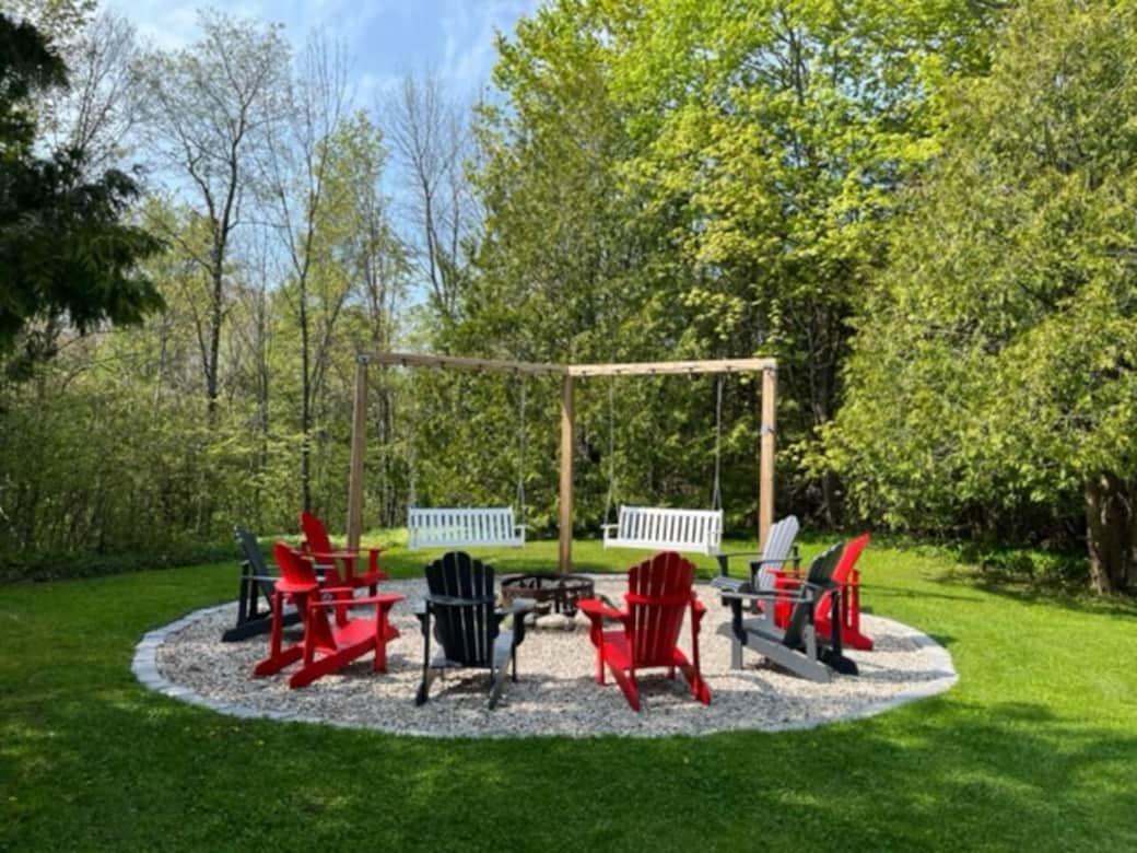 The outdoor living space offers spectacular views of the gardens and riverfront and includes a fire pit area with Muskoka chairs.