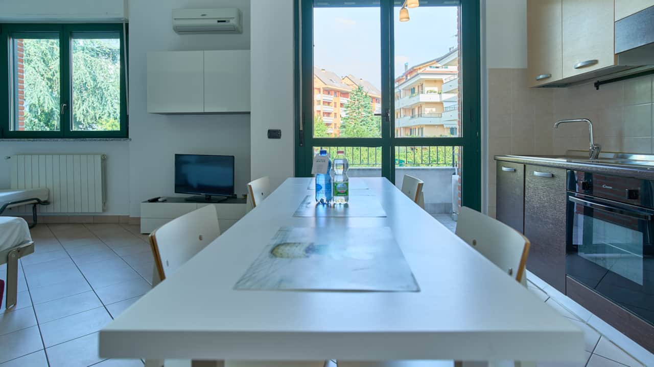 Mesa de comedor larga con sillas junto a la cocina