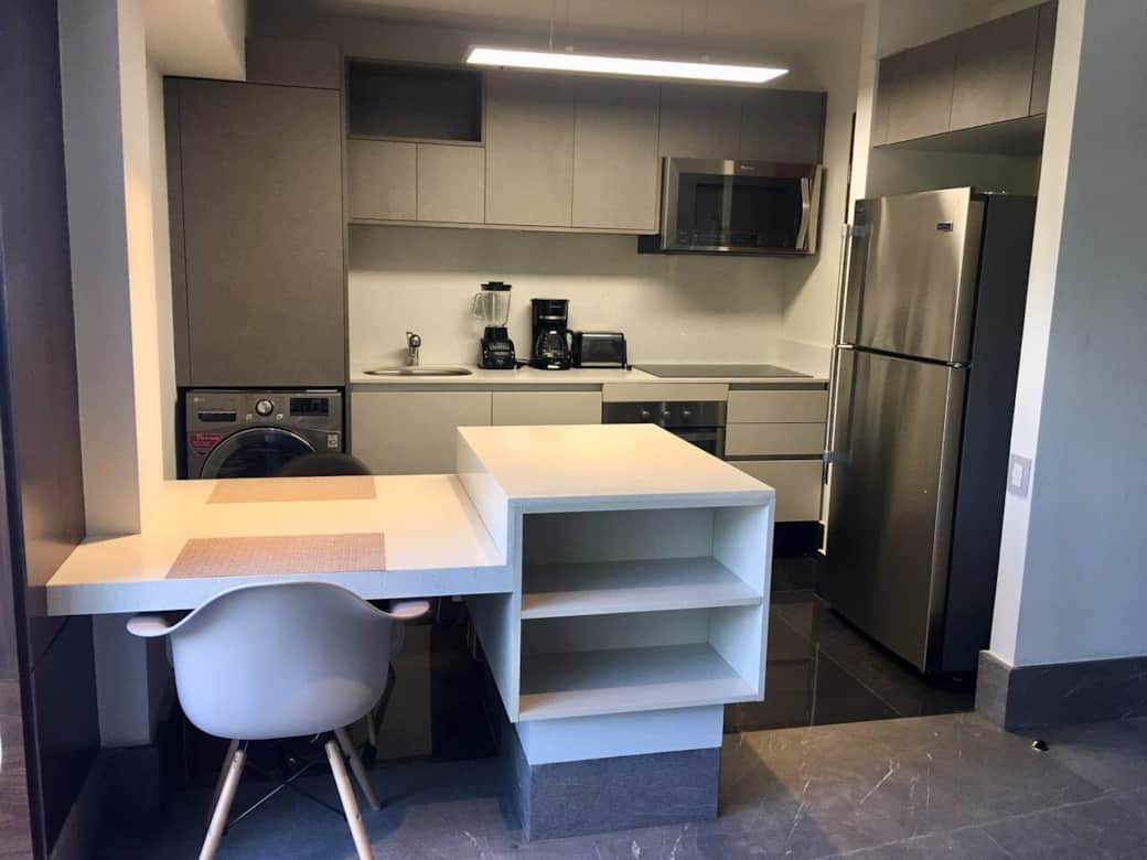 Cocina equipada con barra comedor frente a sala