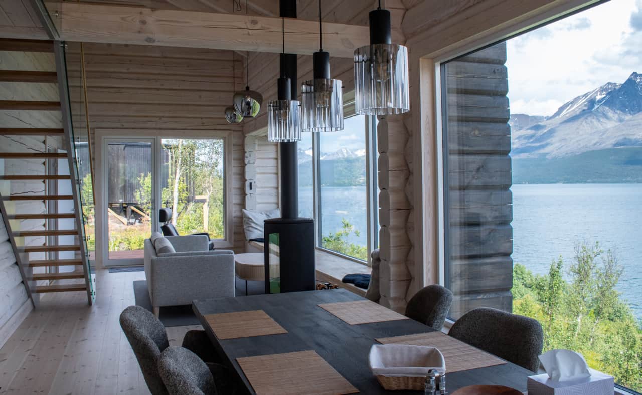 Pale timber stairs rise past the sofa, the water always in frame.