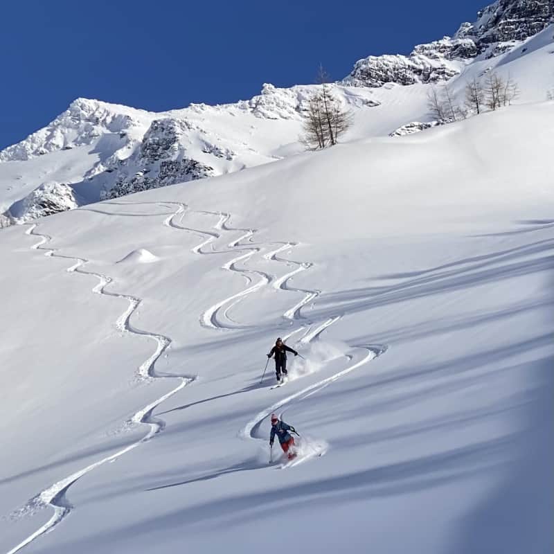 Traces de ski hors-piste dans la poudreuse vierge face aux sommets enneigés, Serre Chevalier Vallée