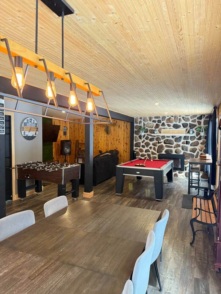 Grande pièce de vie avec billard, baby-foot et mur de pierre