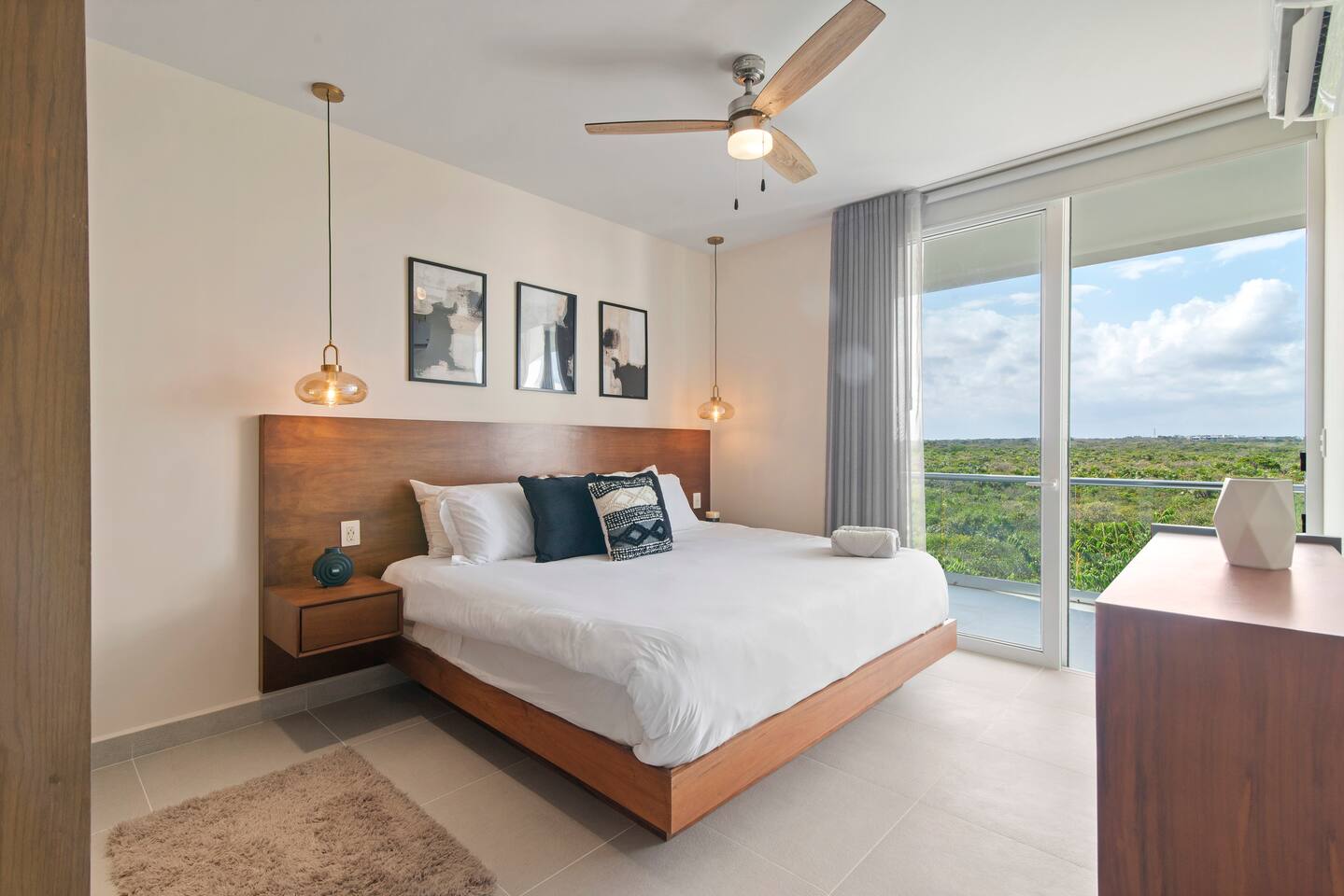 Spacious bedroom featuring a king-size bed, AC, a ceiling fan, and room-darkening shades for a restful stay. Enjoy direct access to your private balcony, where you can relax and take in beautiful Akumal jungle views.