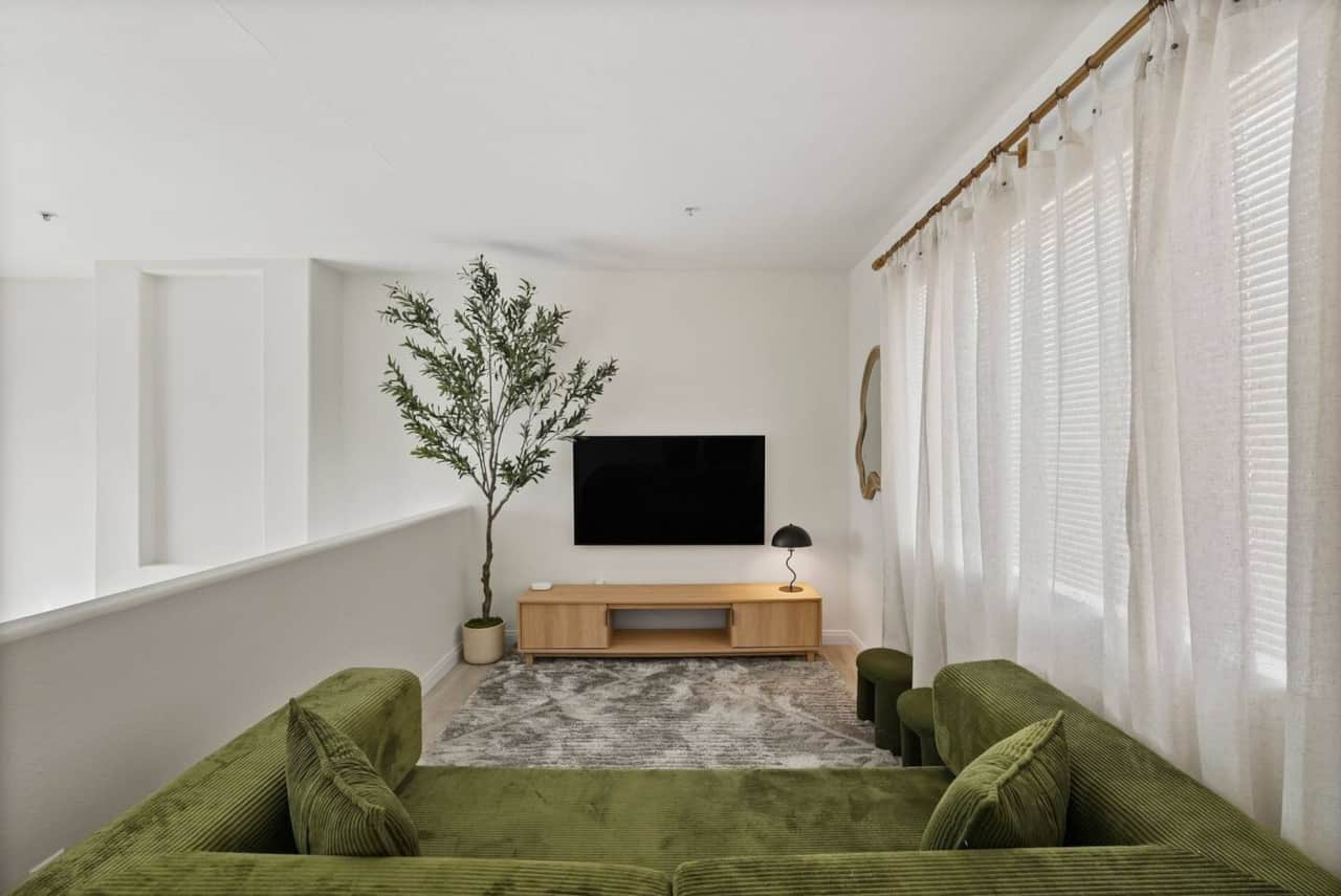 Loft movie room offers a wall-mounted TV, cozy seating, and a fireplace.