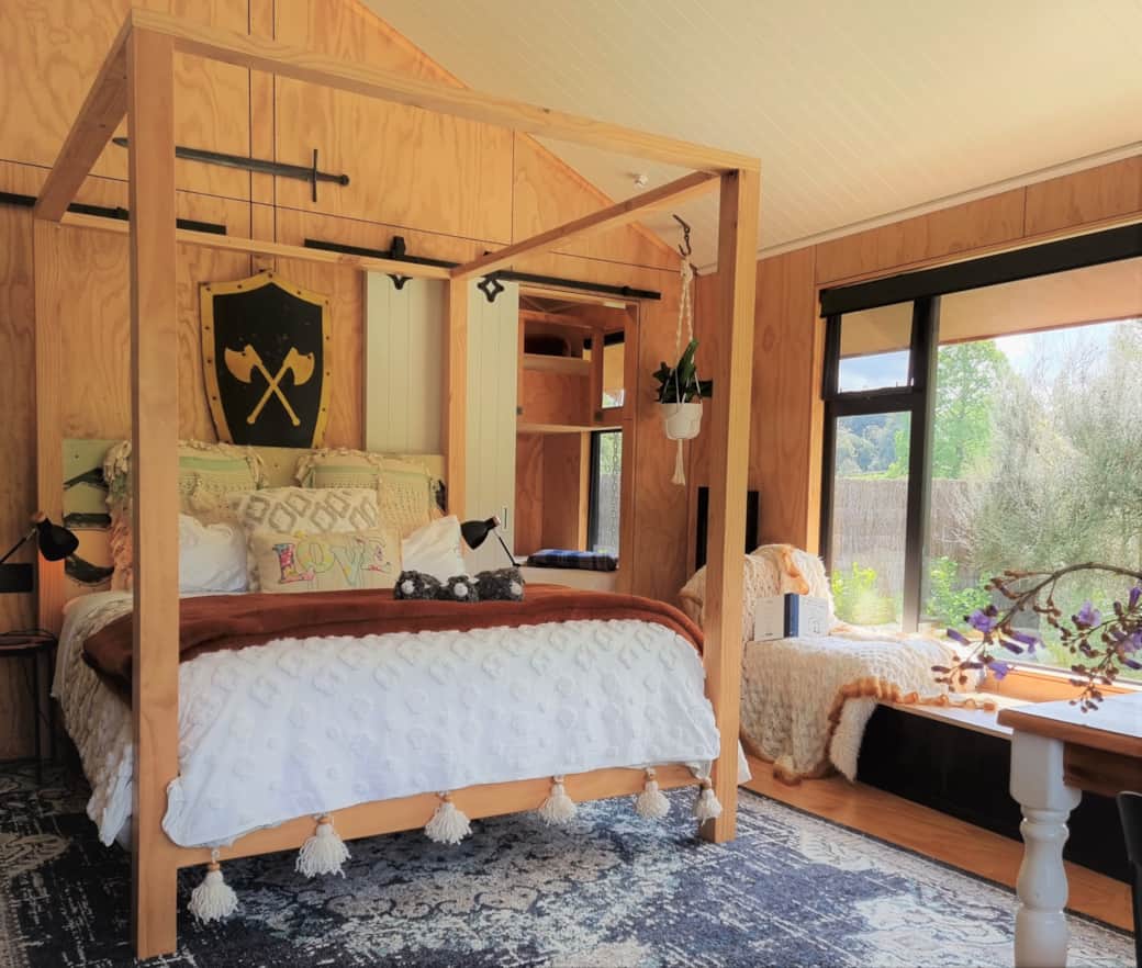 Hand-built four-poster king bed inside River Song Cabin Ripples Retreat – romantic farm stay Waitomo