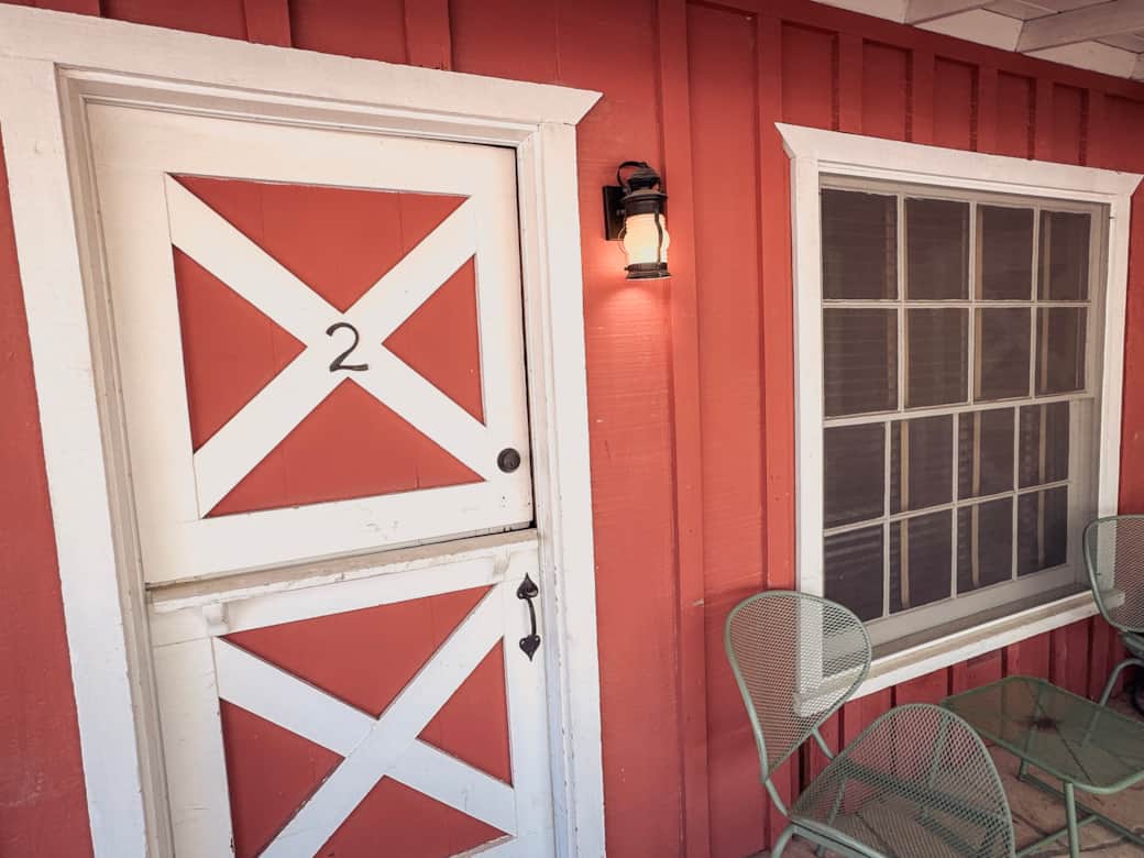 Vintage red-and-white Dutch door with patio chairs at Joshua Tree desert motel