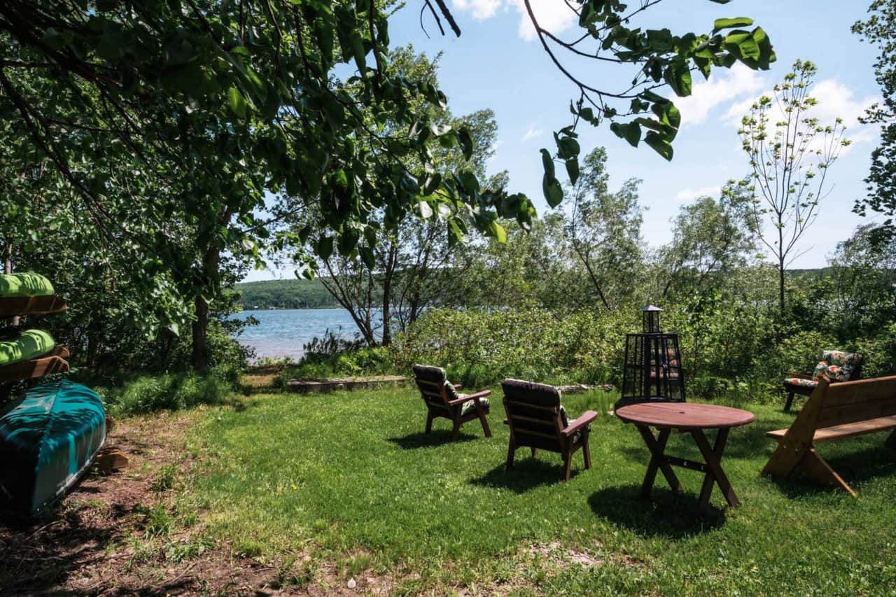 Zone foyer au bois au bord du lac avec chaises, banc et table.  Avec canot, 2 kayaks et 1 paddle.