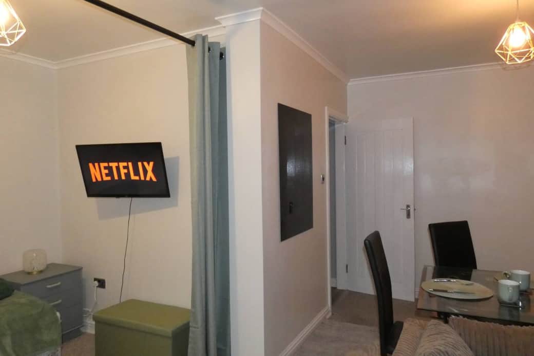 Living room with trundle bed, dining area, sofa and smart TV with wireless mobile screen sharing