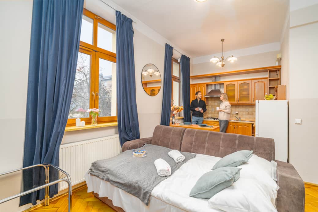 Open-plan space with a bed, sofa and kitchenette, bright interior with a functional layout.