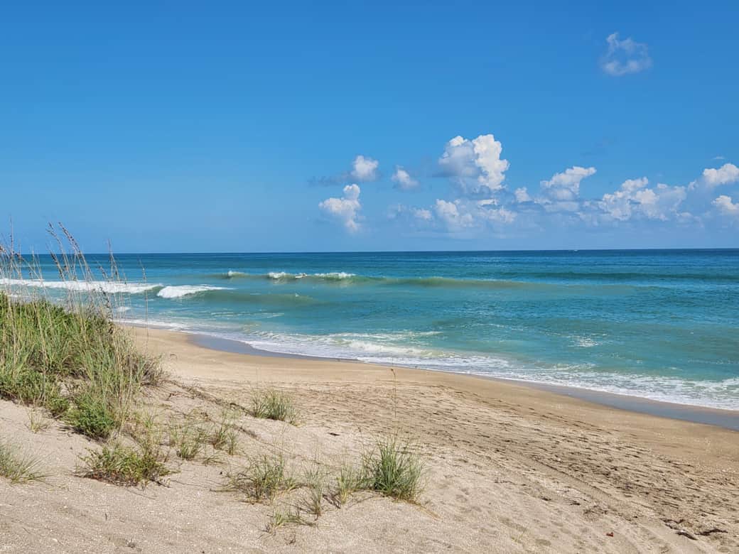 Sandy beach with waves and surfer