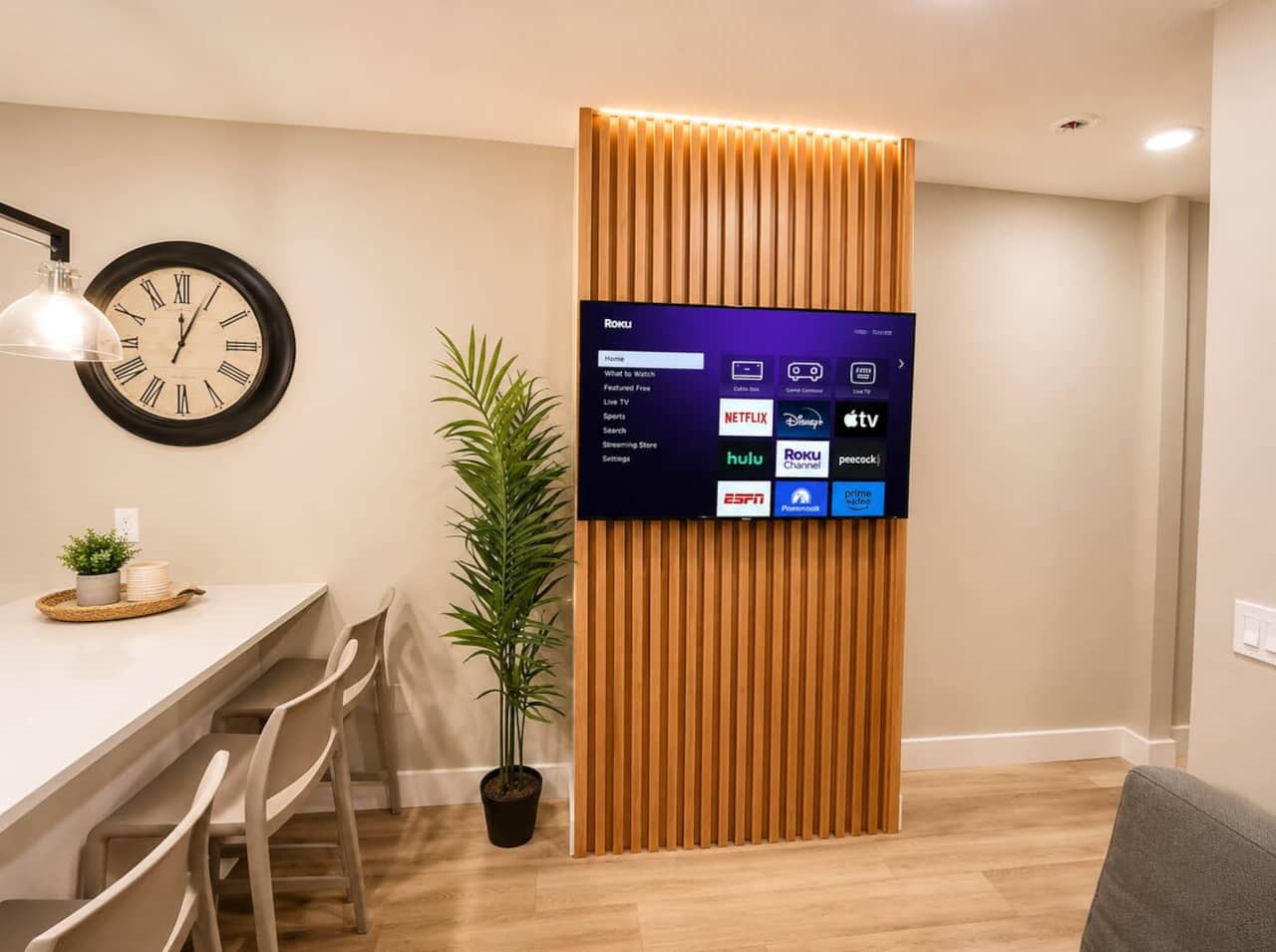 Living room featuring a futon sofa bed and flat-screen TV, perfect for relaxing.
The space flows directly into the modern kitchen with a quartz island and seating, plus a convenient door leading to the backyard—great for indoor-outdoor living.