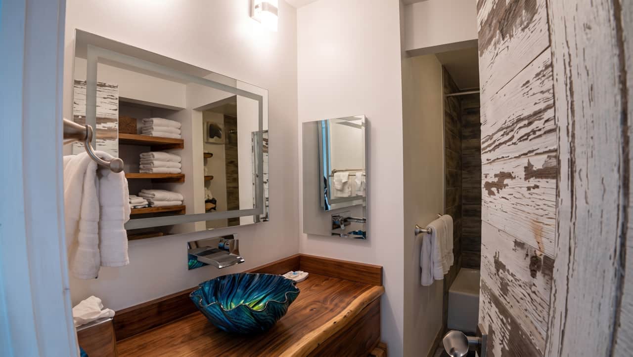 Updated bathroom with a unique vessel sink, wood countertop, and convenient towel storage.