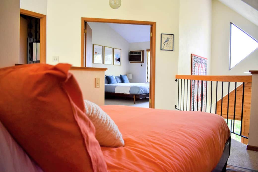 View from the loft bed into the living room and Bedroom 1. The bathroom is accessible from the hall.