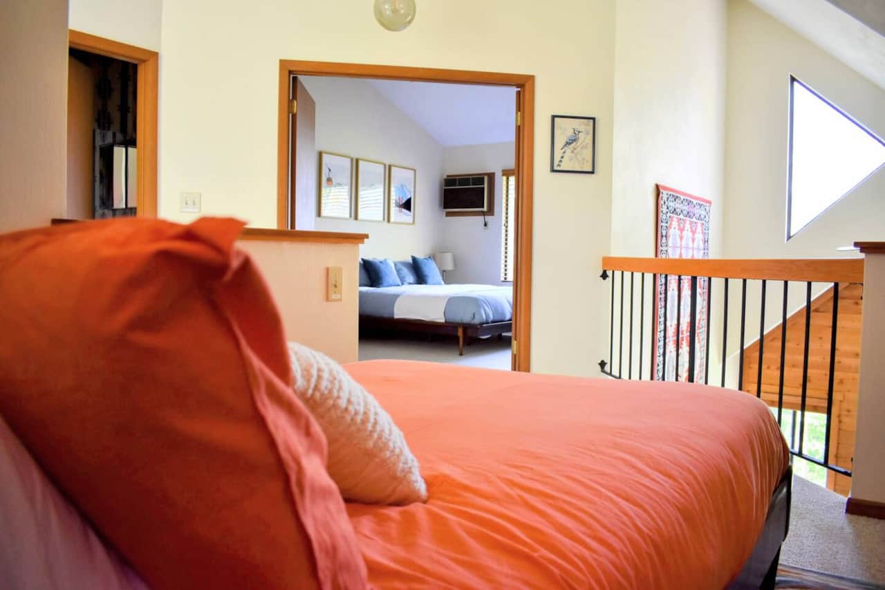 View from the loft bed into the living room and Bedroom 1. The bathroom is accessible from the hall.