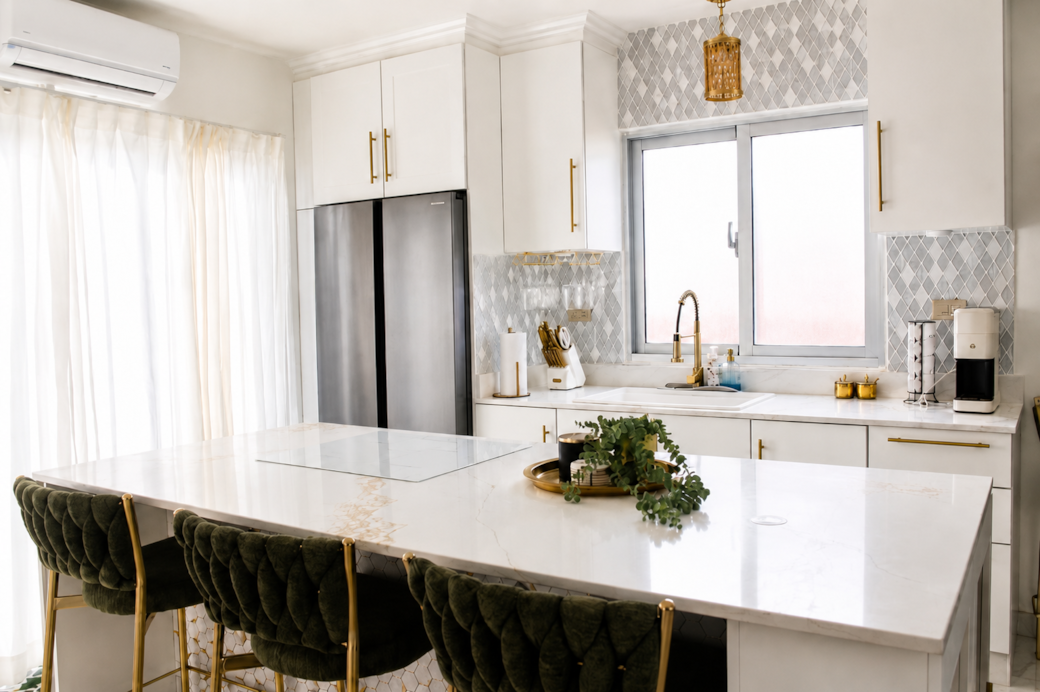 Bright modern kitchen with marble island, velvet stools, and gold accents. Bright modern kitchen with marble island, velvet stools, and gold accents.