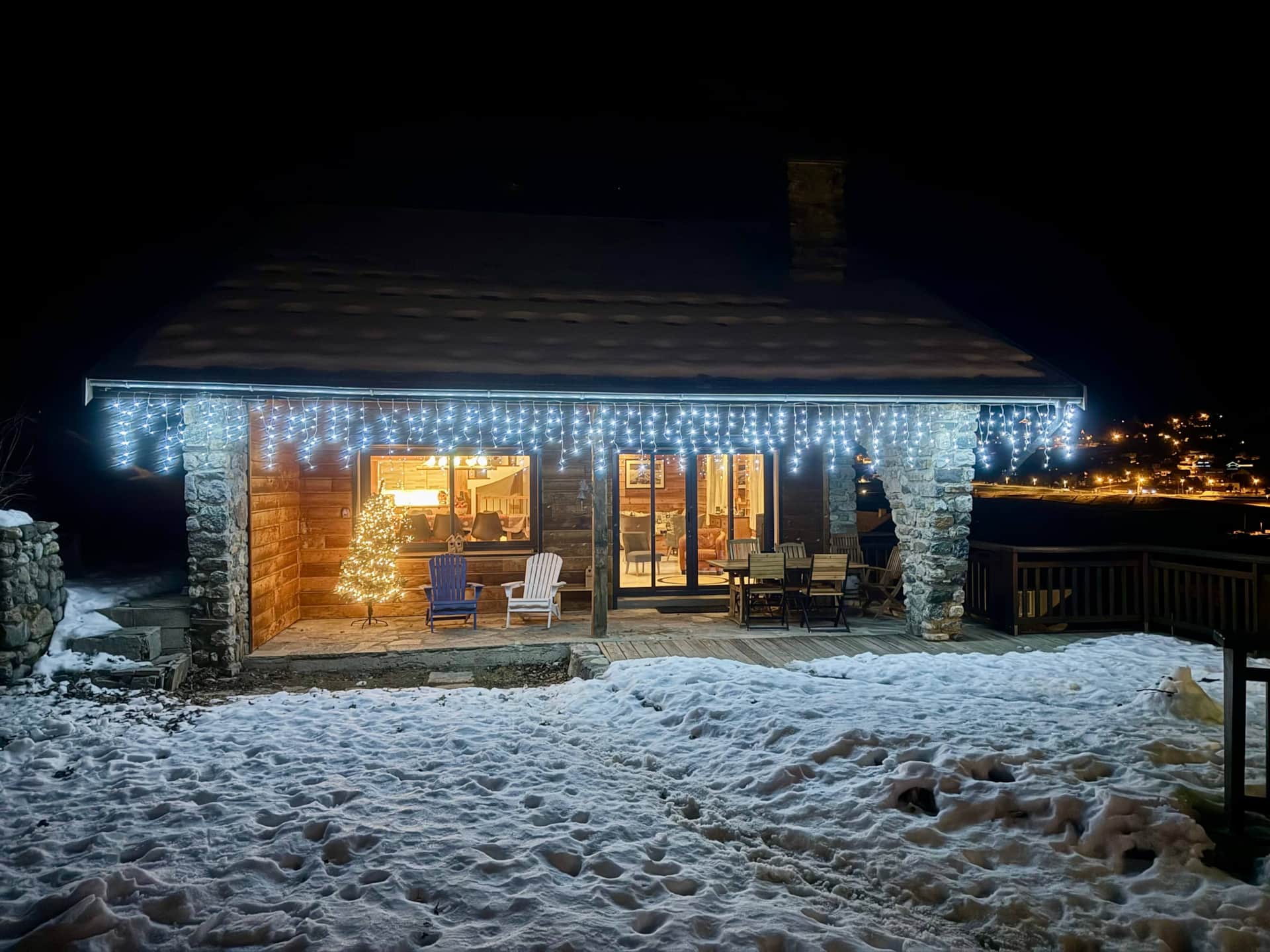 Chalet Mont Milo illuminé la nuit en hiver, terrasse décorée de guirlandes et sapin de Noël, Serre Chevalier Vallée