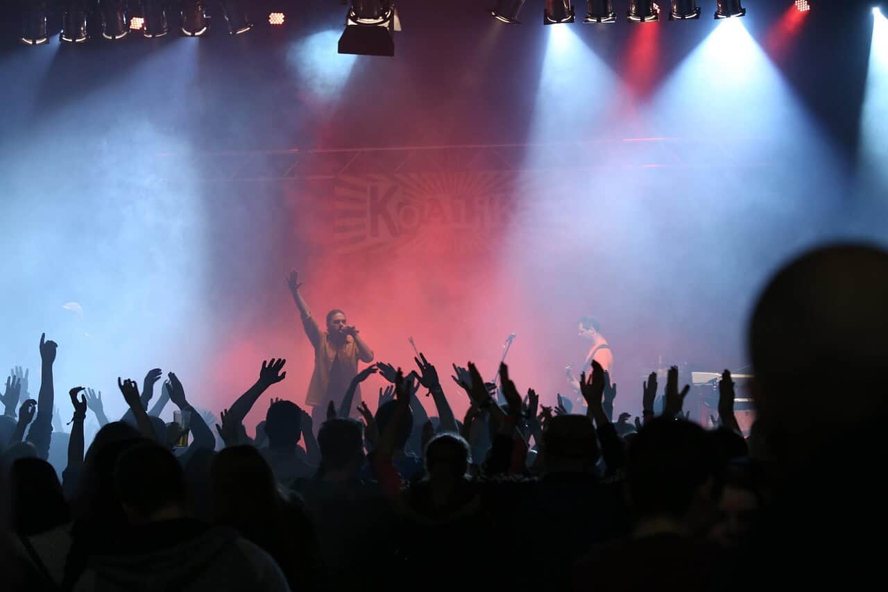 Live-Konzert mit Band auf der Bühne und jubelndem Publikum im Vordergrund