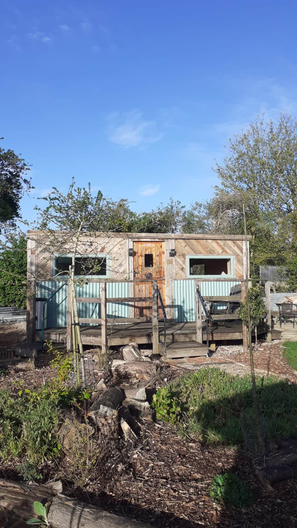 The Den Hut glamping pod for 2 has a rustic exterior with wrinkly tin and pallet wood fascia.