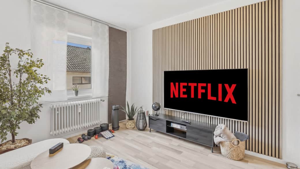 Helles Wohnzimmer mit großem Flachbildschirm, Netflix-Logo, Holzlamellenverkleidung und Zimmerpflanz