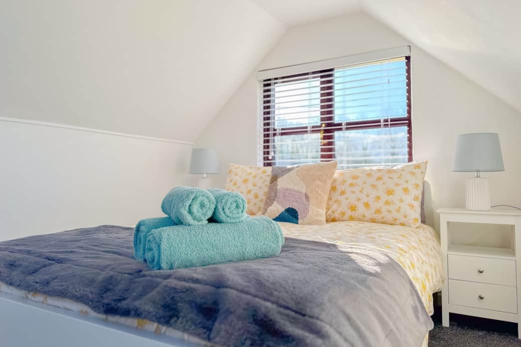 Double bed with towels, bedside tables and garden view