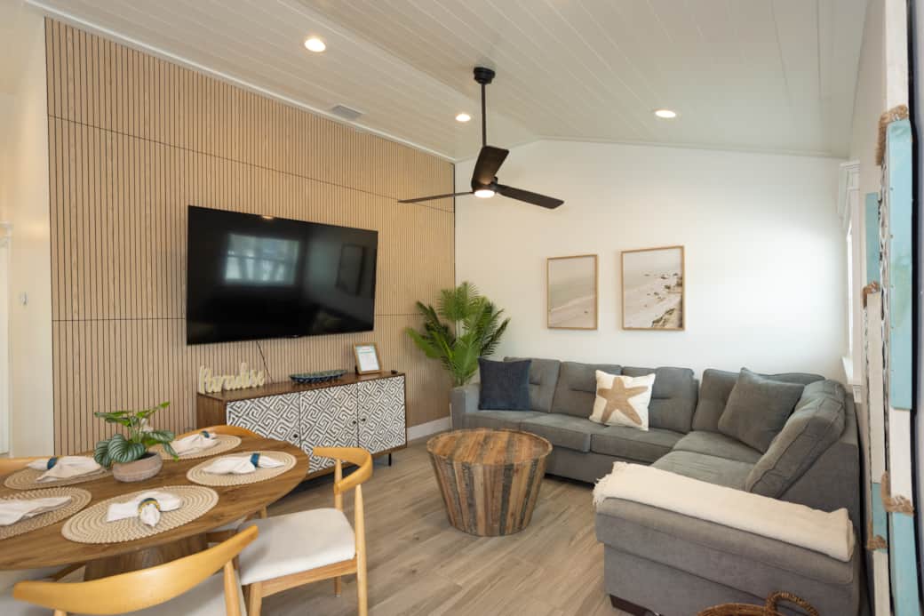 Comfy Coastal living room nights—plush sectional sofa, smart TV, and a dining table for five.