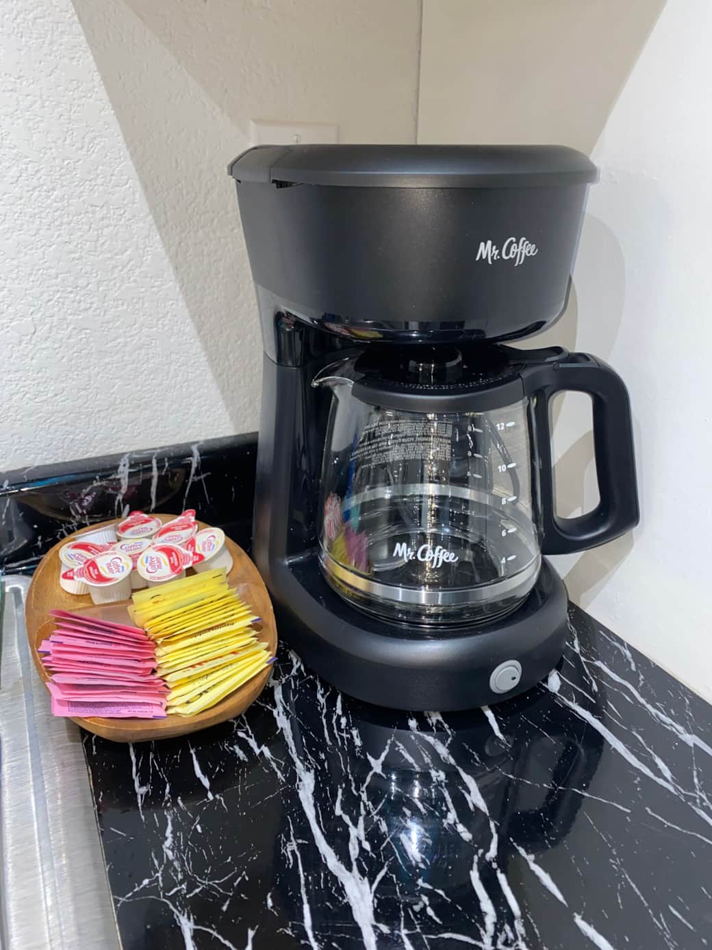 Coffee maker with coffee, sugar, creamer and coffee filters. Two to go coffee cups with lids.
