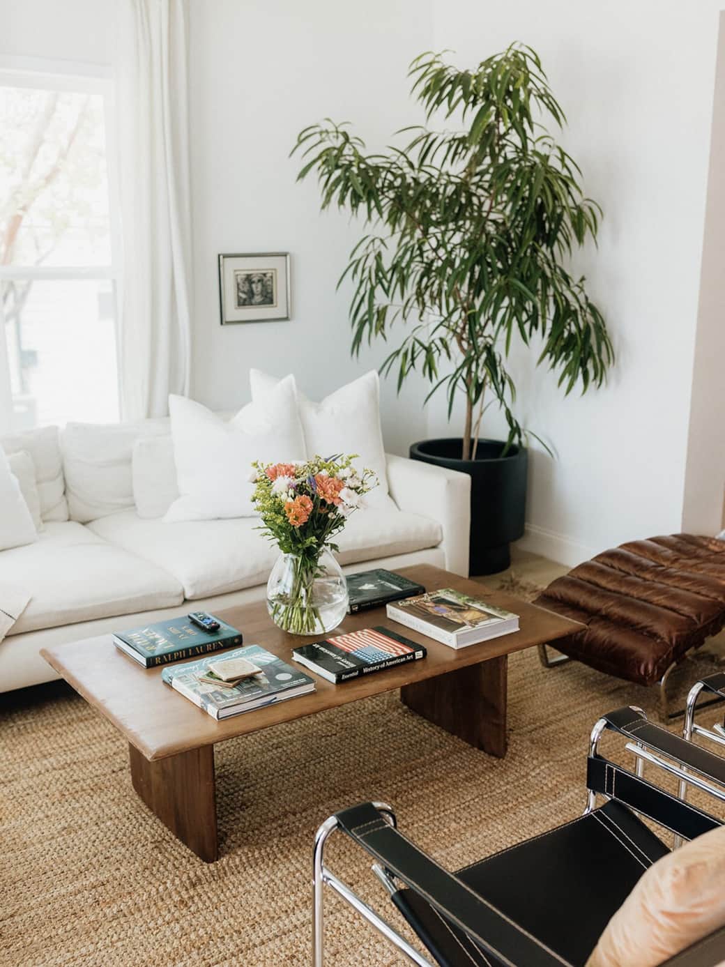 Light-filled and effortlessly refined, our living room layers soft linen seating, a sculptural leather, and warm wood tones for a relaxed, elevated feel. Styled with curated books and collected art, made for slow mornings and cozy nights 