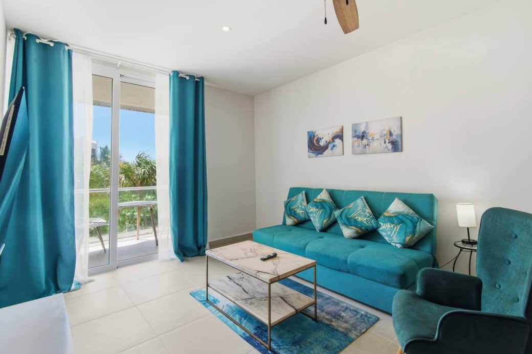 Relax in this inviting living room featuring a comfortable sofa bed, Smart TV, A/C, and ceiling fan for a cool and relaxing stay. Step directly onto the private balcony with outdoor furniture and enjoy refreshing sea breezes and partial ocean views.