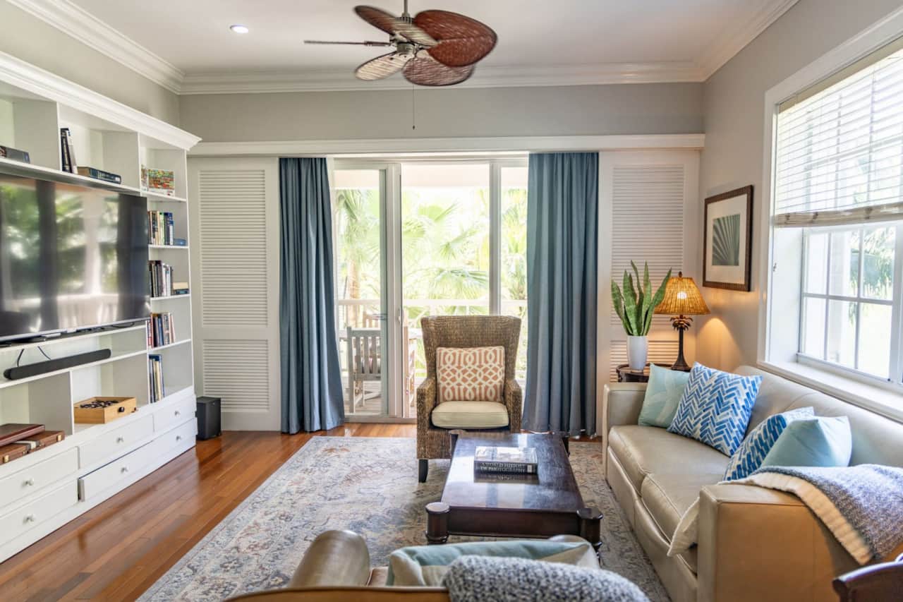 Living room with leather sofa, wicker armchair and sliding doors to the palm-view balcony