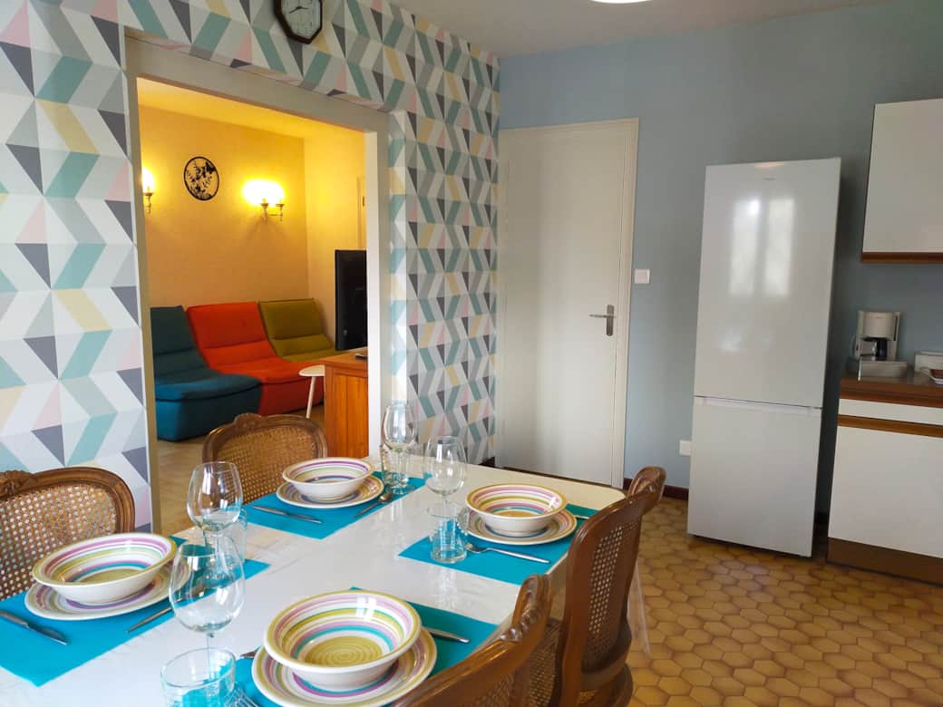 Chez Tata Malou - cuisine équipée ouverte sur salon fauteuils tissu TV écran plat accès coiloir cham