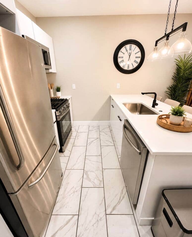 Modern, fully equipped kitchen featuring a spacious island with seating for four, stainless-steel appliances, plenty of counter space, and a convenient door leading directly to the backyard.