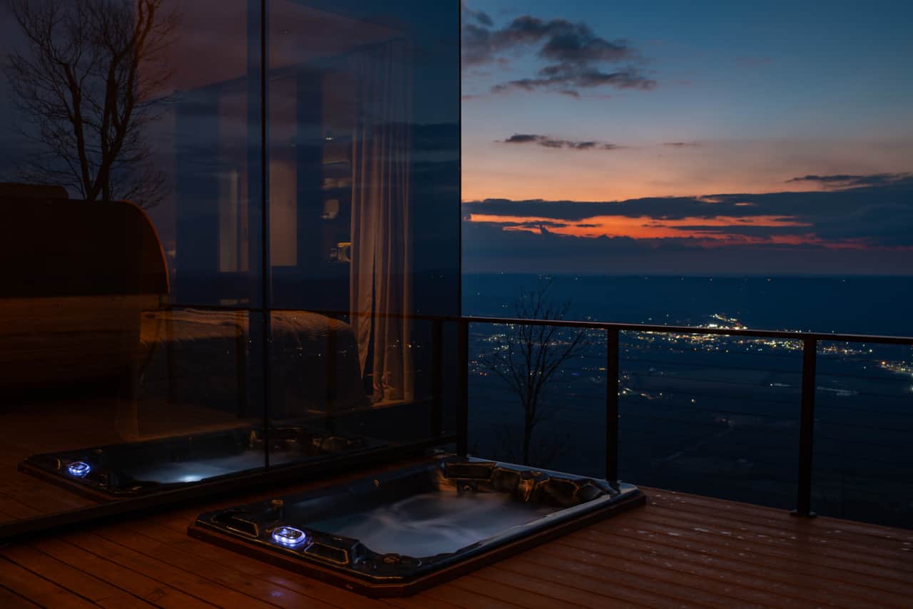 Evening glow from the hot tub and bedroom, with soft light and mountain views beyond.