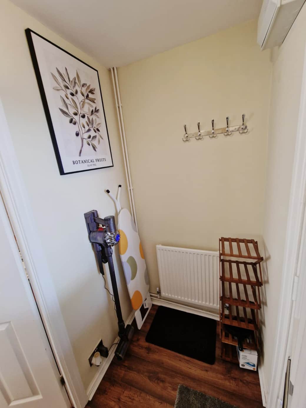 Entrance hall with dyson hoover, coat hooks, ironing board and luggage storage.