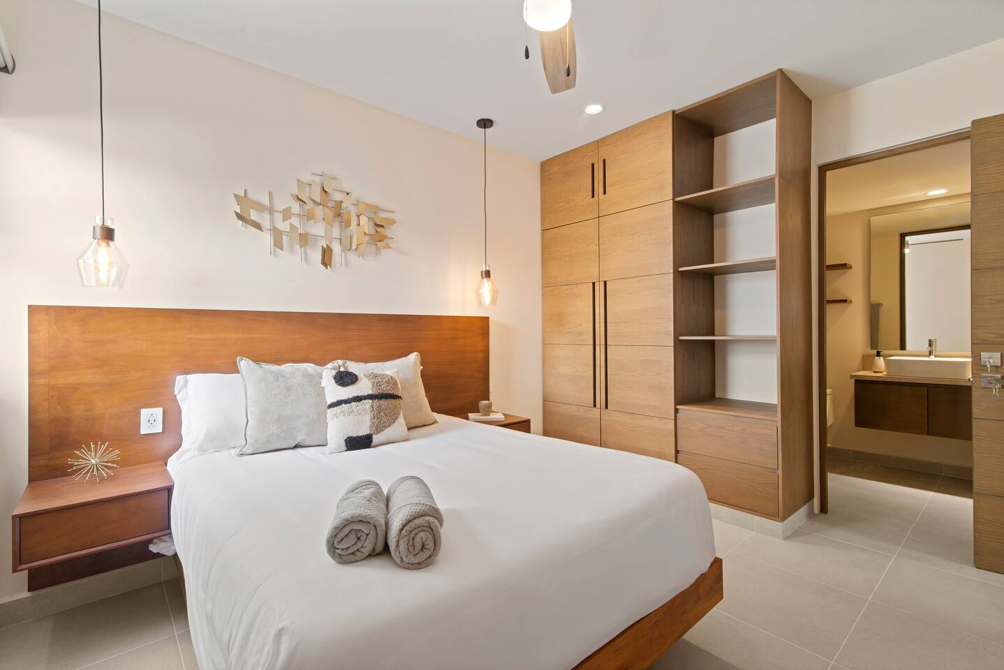 This inviting bedroom features a queen-size bed, AC, a ceiling fan, and room-darkening shades for a restful stay. It also offers a full wardrobe and a private en-suite bathroom for added comfort and convenience.