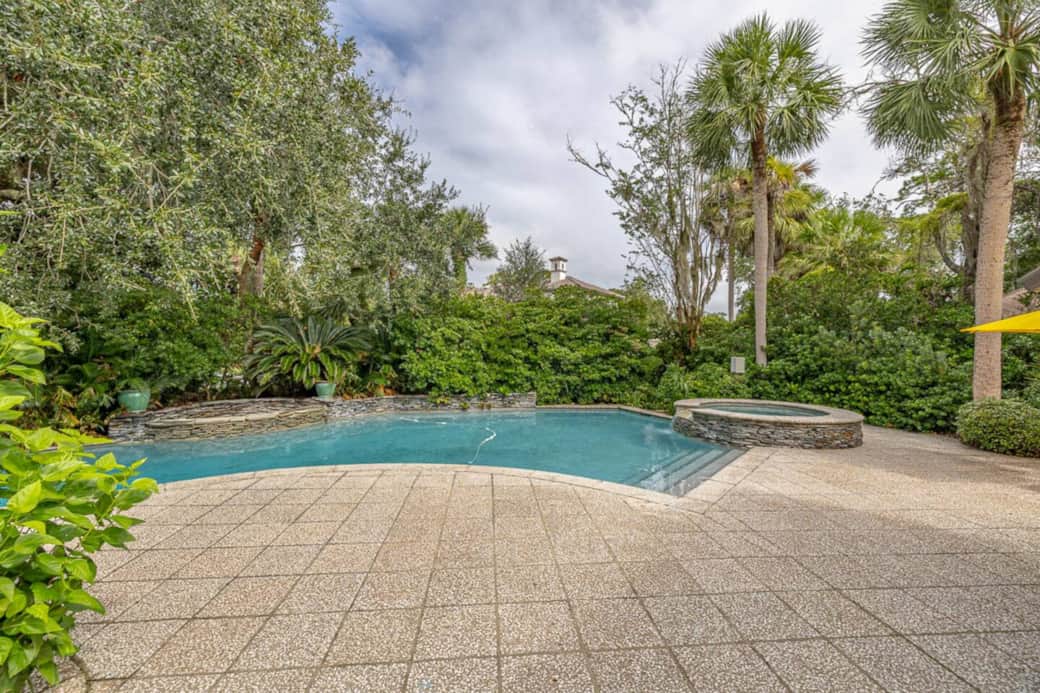This back patio leads to the gorgeous and serene pool that not only has a hot tub (to the right), but also a beautiful water feature (to the left), making the house feel like your own tropical oasis. 