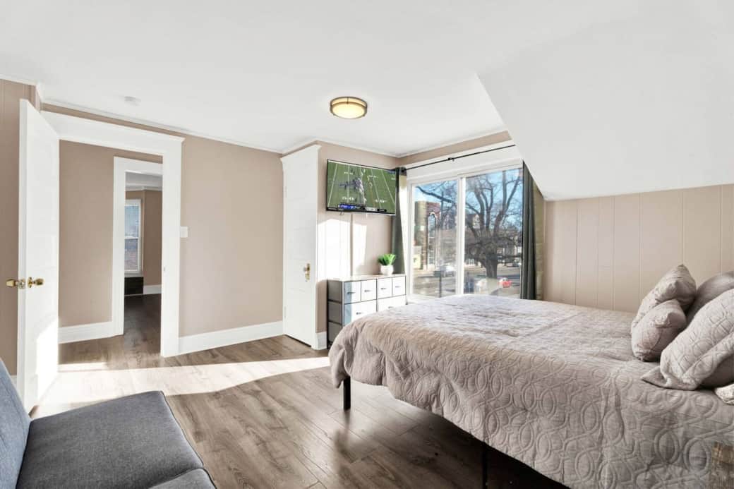 Queen bed, couch, closet with hangers, dresser, bedstand with lamp, charging station, alarm clock, and TV.