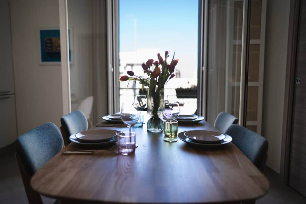 A spacious dining table perfect for shared meals, morning coffee, or planning your next adventure in Monopoli. The balcony access adds an airy, indoor-outdoor feel to the space.