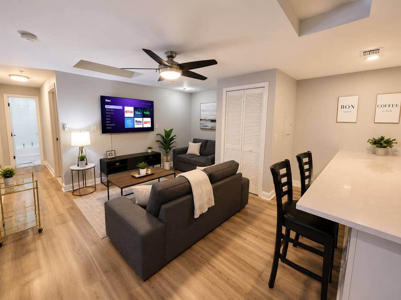  living space featuring a comfortable futon sofa bed, perfect for extra guests. The room flows into a modern kitchen with a beautiful quartz island, to relax, dine, or work. Complete with a Roku Smart TV and stylish furnishings.