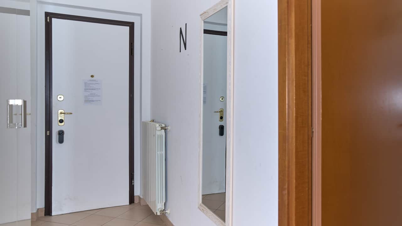 Entrée avec porte, miroir sur pied et radiateur