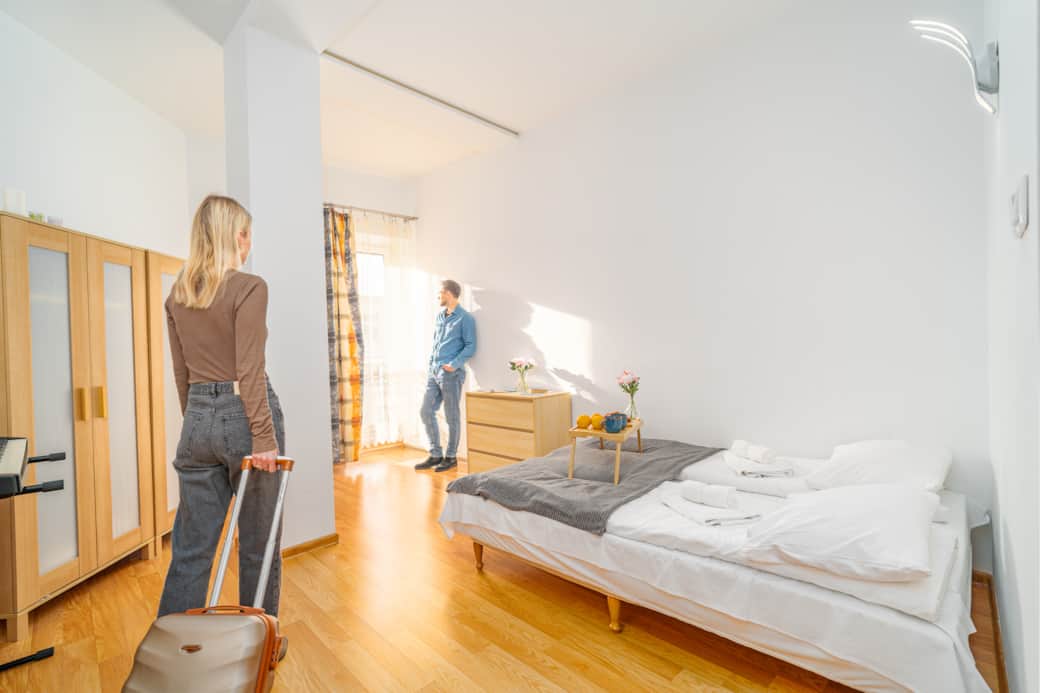 Jasna sypialnia z dużym oknem i drewnianą podłogą.