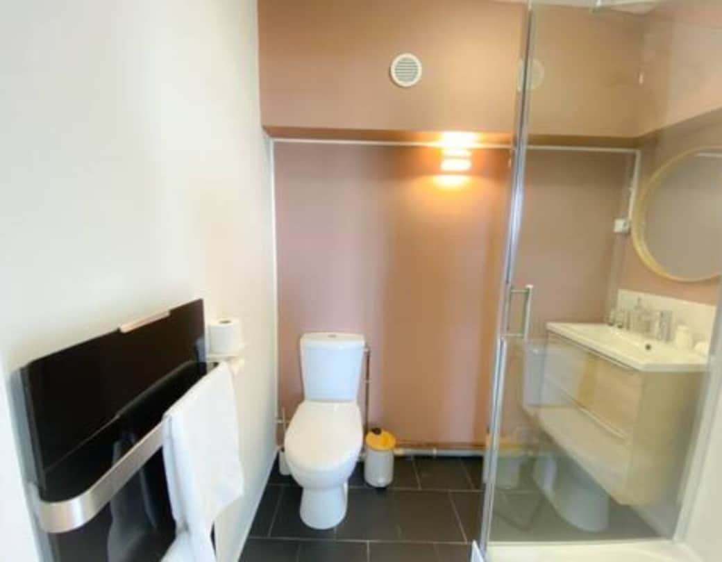 Salle de bain moderne avec douche, WC et sèche-cheveux.