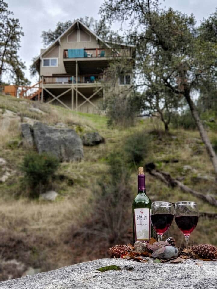 Wine by the river with cabin views — grab a bottle, head to the rocks, and toast to the great outdoors