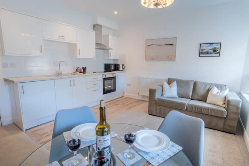 Living area with sofa, kitchen and set dining table in the Windermere apartment