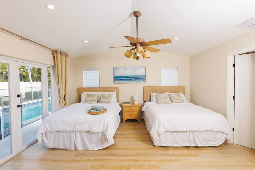 The master bedroom boasts two queen beds, a TV, and a private bathroom. During the day, it gets the perfect amount of natural light, and at night, the curtains ensure a restful sleep.
