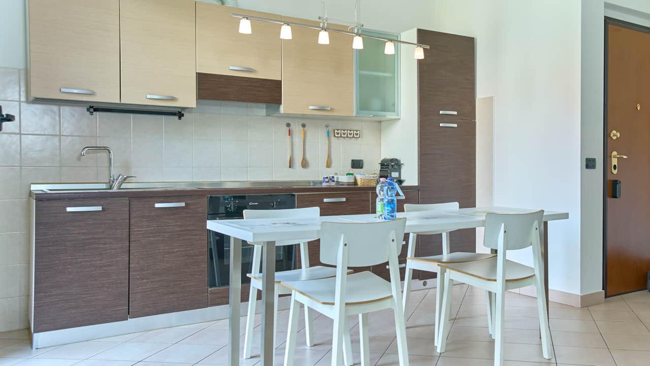 Cocina con mesa, sillas blancas y muebles de madera