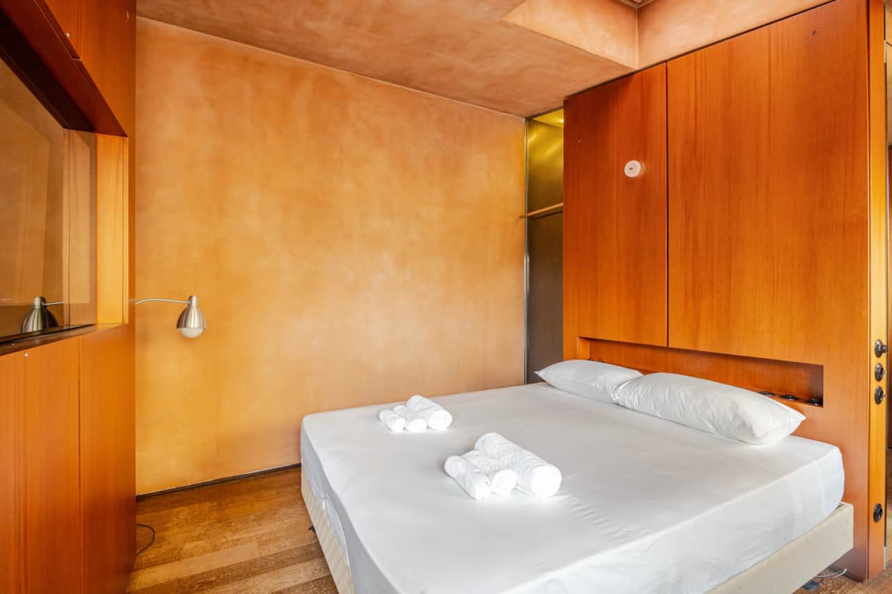 Cama de matrimonio con ropa blanca y toallas dobladas